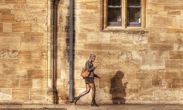 A student walking in-front of old college buildings