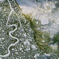 Aerial photograph of a river system in a green and rocky landscape. 